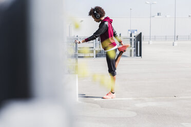 Young woman stretching on parking lot - UUF007297