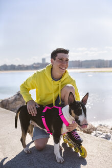 Porträt eines lächelnden Inline-Skaters mit seinem Bullterrier - MGOF001846