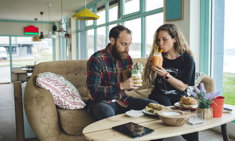 Ehepaar frühstückt in einem Café und trinkt Bio-Säfte, lizenzfreies Stockfoto