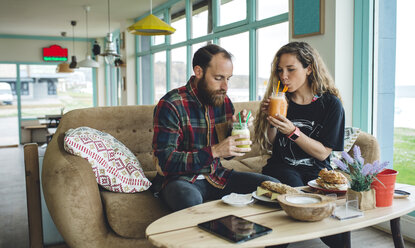Ehepaar frühstückt in einem Café und trinkt Bio-Säfte - DAPF000094