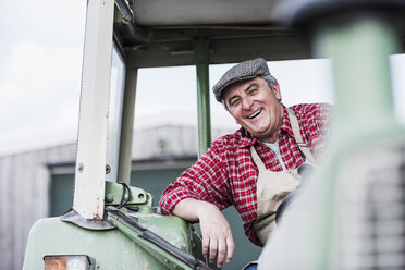 Porträt eines lächelnden Landwirts auf einem Traktor - UUF007330