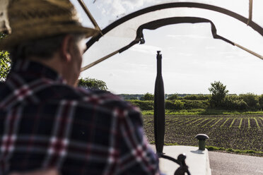 Landwirt auf Traktor neben einem Feld - UUF007334