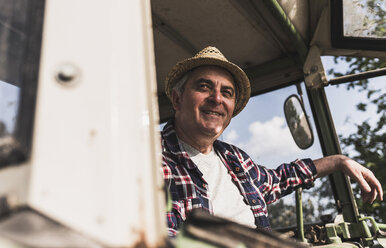 Porträt eines lächelnden Landwirts auf einem Traktor - UUF007335