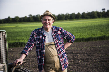 Porträt eines lächelnden Bauern vor einem Feld - UUF007337