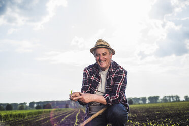 Porträt eines lächelnden Landwirts auf einem Feld mit Ernte - UUF007343