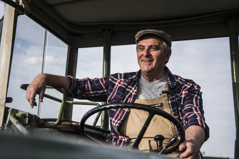 Porträt eines lächelnden Landwirts auf einem Traktor, lizenzfreies Stockfoto