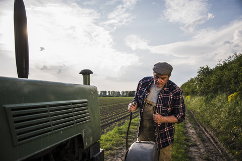Landwirt steht neben einem Traktor auf einem Feld, lizenzfreies Stockfoto