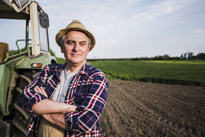 Farmer standing next to tractor at a field - UUF007366