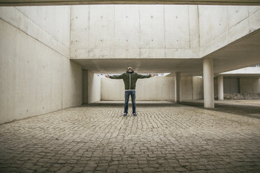 Mann mit ausgestreckten Armen und zurückgelegtem Kopf in moderner Architektur - ABZF000529