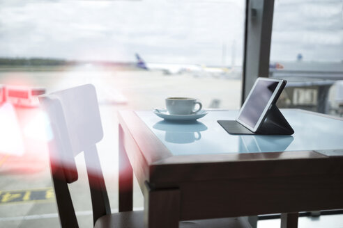 Kaffeetasse und digitales Tablet auf dem Tisch im Flughafen - RIBF000391