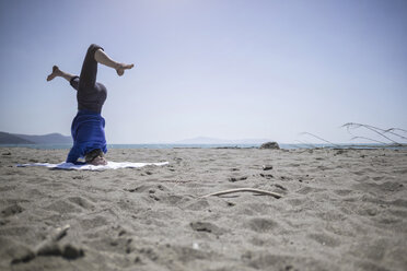 Italien, Frau macht Yoga-Übungen am Strand - RIBF000398