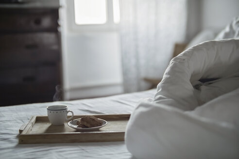 Holztablett mit einer Tasse dampfendem Kaffee und Keksen auf dem Bett - RIBF000401