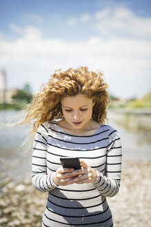 Italien, Verona, Porträt einer Frau, die auf ihr Smartphone schaut - GIOF001038