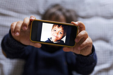 Kleiner Junge hält ein Handy mit einem Bild von sich selbst - VABF000504