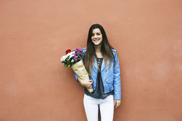 Lächelnde junge Frau hält einen Blumenstrauß - EBSF001367