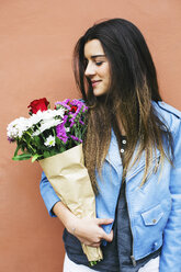 Smiling young woman holding bunch of flowers - EBSF001369