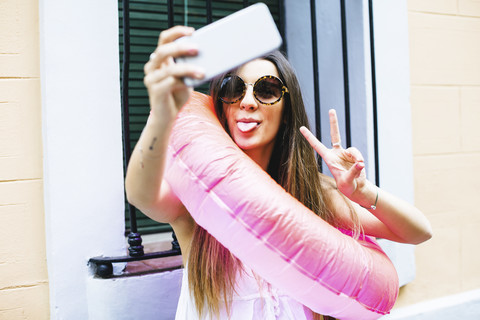 Verspielte junge Frau mit Badering, die ein Selfie macht, lizenzfreies Stockfoto