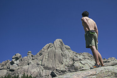 Spain, shirtless climber using his chalk bag in front of the Santillana's wall in La Pedriza - ABZF000545