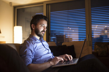 Man sitting on sofa, using laptop - HAPF000424