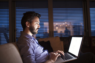 Man sitting on sofa, using laptop - HAPF000425