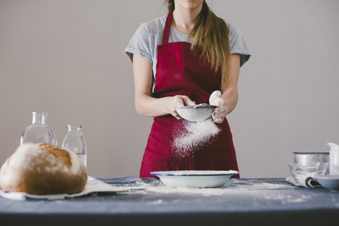 Frau bei der Zubereitung von selbstgebackenem Brot, das Mehl wird gesiebt, lizenzfreies Stockfoto