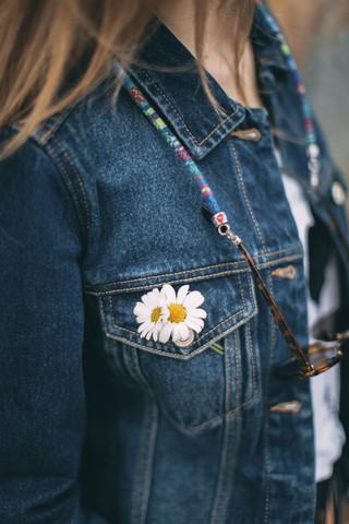 Gänseblümchen an der Tasche der Jeansjacke einer Frau, lizenzfreies Stockfoto