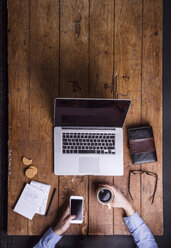 Man with coffee cup and smartphone at his desk - HAPF000446