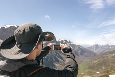 Spain, Asturias, Somiedo, man taking a picture in mountains - MGOF001848