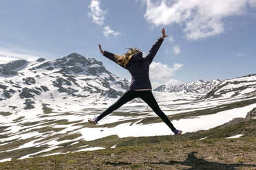 Spain, Asturias, Somiedo, playful woman jumping in mountains - MGOF001860