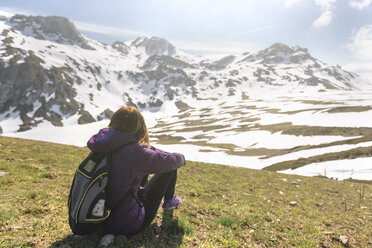 Spanien, Asturien, Somiedo, Frau schaut auf einer Wiese sitzend in die Landschaft - MGOF001862