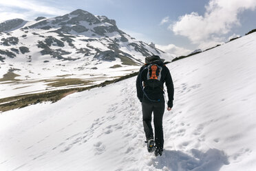 Spanien, Asturien, Somiedo, Mann beim Wandern in verschneiten Bergen - MGOF001867