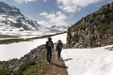 Spain, Asturias, Somiedo, couple hiking in snowy mountains - MGOF001868