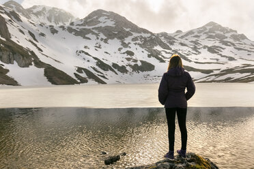 Spain, Asturias, Somiedo, woman standing at mountain lake - MGOF001881