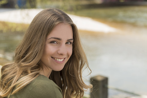 Porträt einer lächelnden jungen Frau an einem Fluss, lizenzfreies Stockfoto