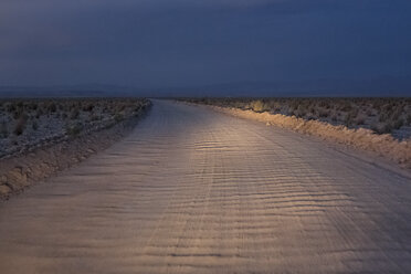 Chile, San Pedro de Atacama, Auto Lichter auf leeren Feldweg in der Abenddämmerung - MAUF000621