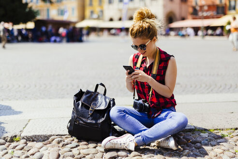 Italien, Verona, Frau auf Stadtplatz schaut auf Handy - GIOF001056