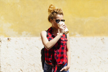 Young woman outdoors drinking from disposable cup - GIOF001062