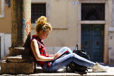 Italy, Verona, woman sitting outdoors using digital tablet - GIOF001068