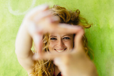 Porträt einer lächelnden Frau, die einen Fingerrahmen formt - GIOF001075