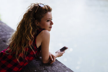 Woman at the riverside holding cell phone - GIOF001086