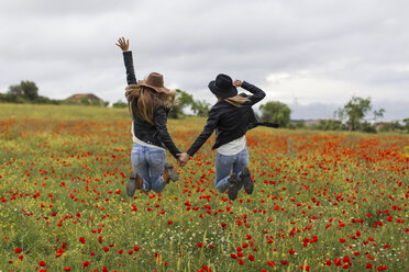 Zwei Frauen springen, Mohnfeld, halten sich an der Hand - JPF000156