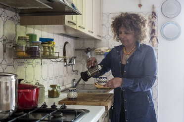 Woman at home pouring coffee into cup - MAUF000629