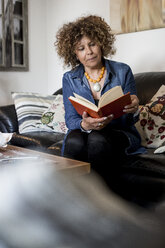 Frau sitzt auf der Couch und liest ein Buch - MAUF000630