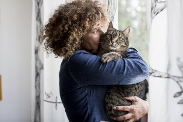 Frau kuschelt mit Katze am Fenster - MAUF000640