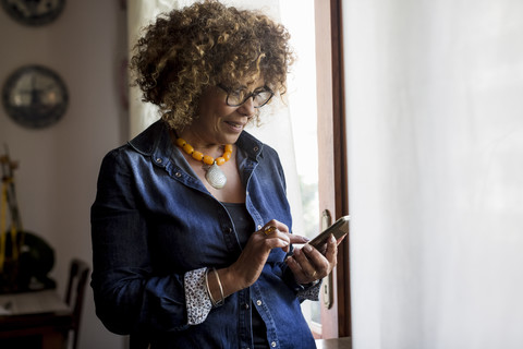 Frau benutzt Phablet am Fenster, lizenzfreies Stockfoto