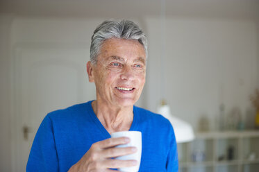 Smiling senior man at home holding cup of coffee - DIGF000499