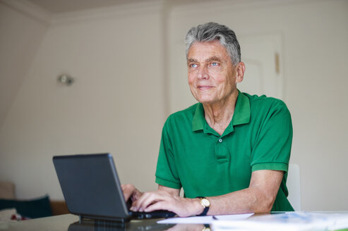 Älterer Mann sitzt am Schreibtisch und benutzt einen Laptop - DIGF000508