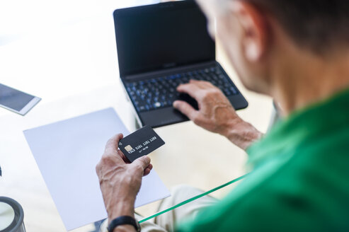 Älterer Mann mit Laptop und Kreditkarte beim Online-Shopping - DIGF000512