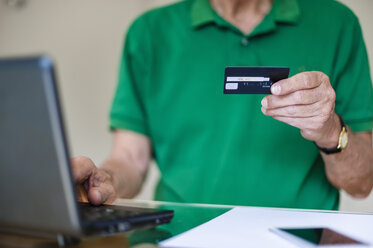 Älterer Mann mit Laptop und Kreditkarte beim Online-Shopping - DIGF000513
