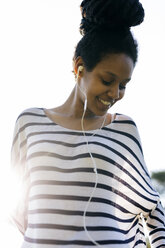 Portrait of smiling woman hearing music with earphones - GIOF001117